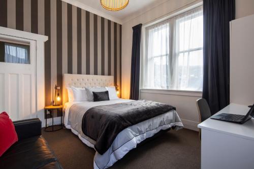 een hotelkamer met een bed en een raam bij Majestic Mansions – Apartments at St Clair in Dunedin