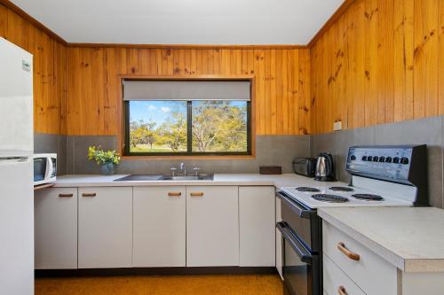 a kitchen with white cabinets and a window at Hunter Hideaway Cottages in Rothbury