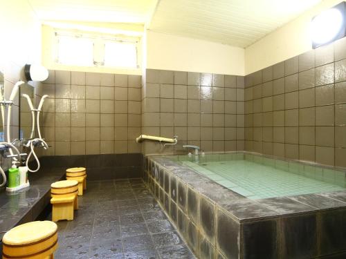 a bathroom with a large tub with toilets and a sink at Oomukou Ryokan in Hakuba