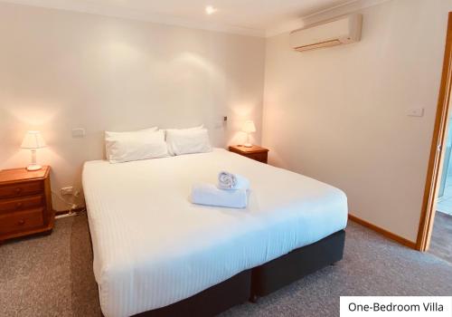 a bedroom with a white bed with a box on it at Pokolbin Village Estate in Pokolbin