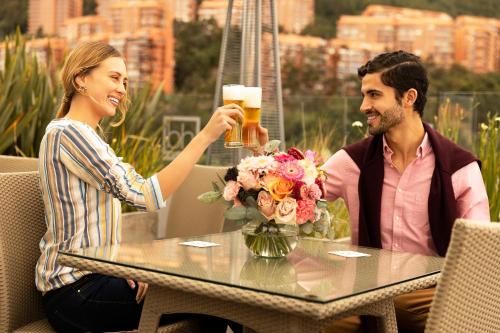 Hotel bh Usaquén في بوغوتا: يجلس رجل وامرأة على طاولة شرب البيرة