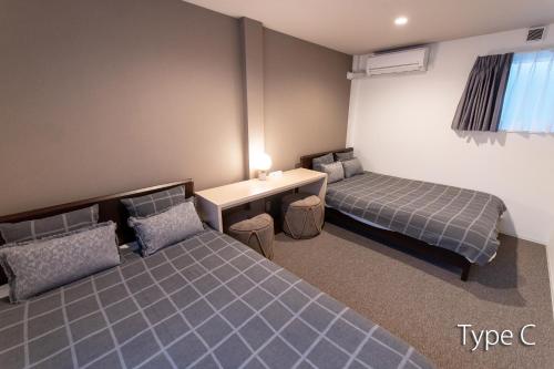 Zimmer mit 2 Betten, einem Tisch und einem Schreibtisch in der Unterkunft Hermitage Nishi Shinjuku in Tokio
