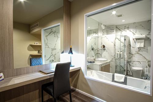 a bathroom with a desk with a chair in front of a window at Gold Orchid Bangkok Hotel in Bangkok