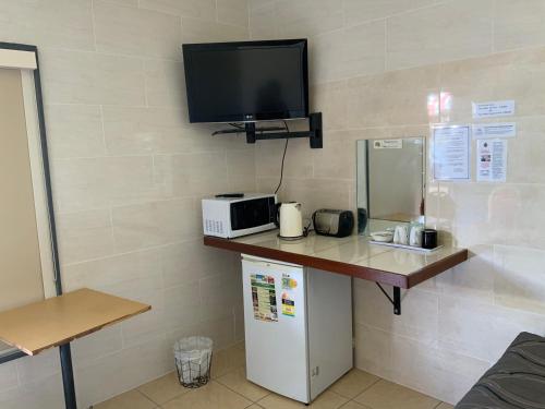 a room with a counter with a tv and a refrigerator at Top 1 Motel in Rockhampton