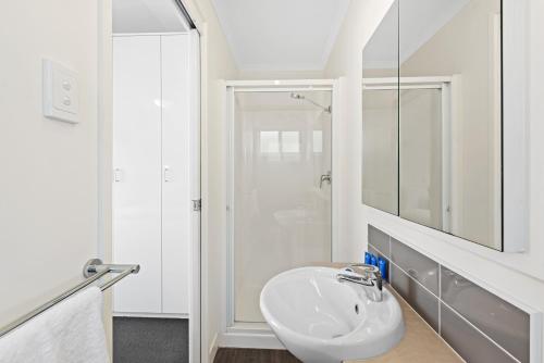 a white bathroom with a sink and a shower at Discovery Parks - Geelong in Geelong