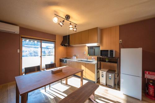 a kitchen with a wooden table and a white refrigerator at Kamo River J~House in Shimmachidōri