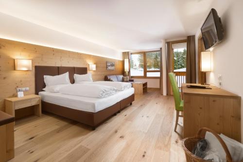 una camera d'albergo con letto e TV di Sporthotel Floralpina ad Alpe di Siusi