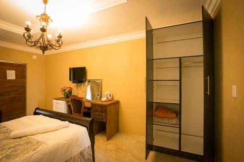 a bedroom with a bed and a desk with a dresser at Ein Gedi Premier Weddings And Conferences in Kimberley