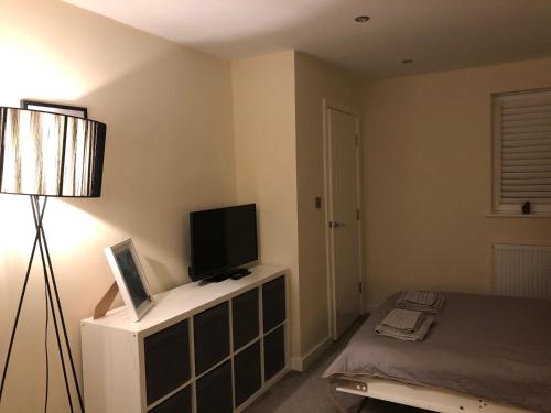 a bedroom with a bed and a tv and a lamp at M60 Modern Studio Appartment with free parking in Denton