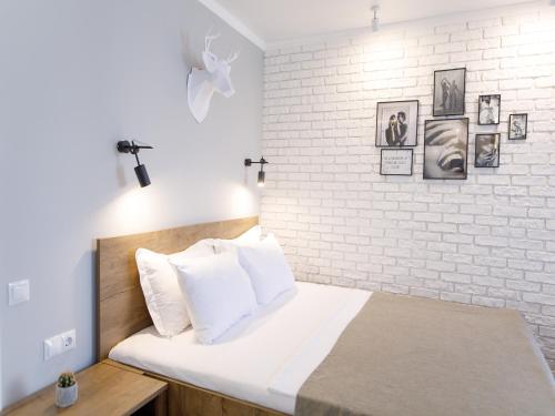um quarto com uma parede de tijolos brancos e uma cama em Studio Suite near Lake with Jacuzzi em Sumy