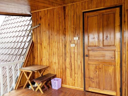 an empty room with a wooden door and a stool at Bansuanphuhong Resort in Chiang Khan