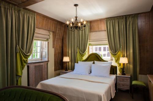 a bedroom with a bed with green curtains and a chandelier at Villa Toscana in Kaliningrad