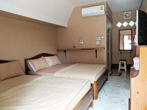 two beds in a small room with a tv at Bansuanphuhong Resort in Chiang Khan