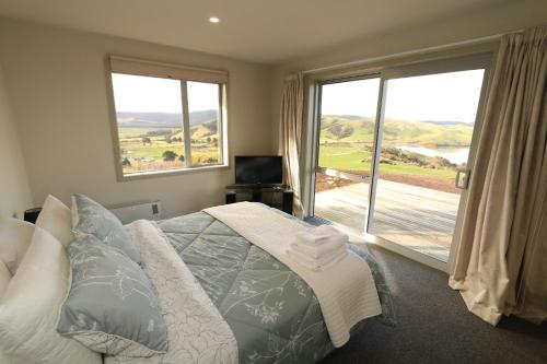 a bedroom with a bed and a large window at Niagara Ridge Retreat Catlins in Niagara