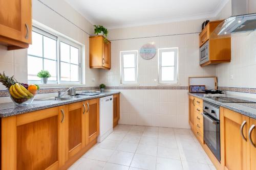 a kitchen with wooden cabinets and a sink at QEV - Santo António in Budens