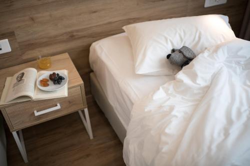 a teddy bear laying on a bed with a book and a plate of food at ibis Styles Athens Routes in Athens