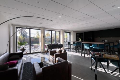 a living room with couches and a table and chairs at Aparthotel Adagio Bâle Mulhouse Aeroport in Blotzheim