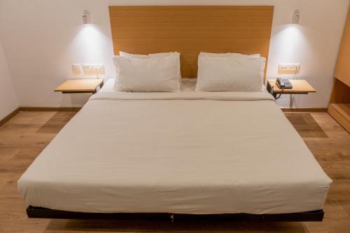 uma grande cama branca num quarto com duas mesas em Madras Regency em Chennai