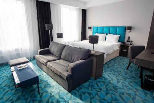 une chambre d'hôtel avec un canapé et un lit dans l'établissement Mirotel Novosibirsk, à Novossibirsk