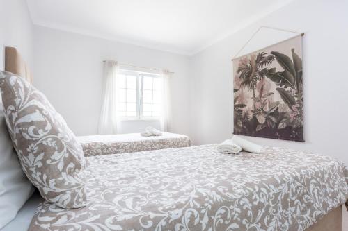 a white bedroom with two beds and a mirror at QEV - Santo António in Budens