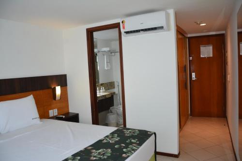 a bedroom with a bed and a door to a bathroom at Natal Plaza requinte, conforto e vista para o mar in Natal