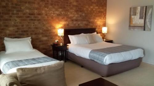 a hotel room with two beds and a brick wall at Federation Motel Resort - Corowa in Corowa