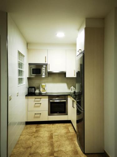 a kitchen with white cabinets and a stainless steel refrigerator at A Casa de Matelos in A Lanzada