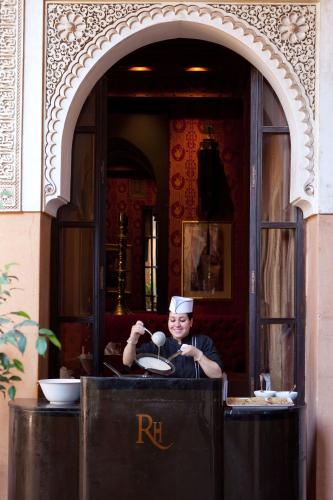 a man in a kitchen taking a picture of a person at Les Jardins De La Koutoubia in Marrakech