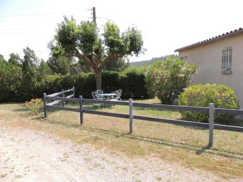 una valla de madera con un banco frente a un árbol en Le Gîte de la Bade, en Villegailhenc