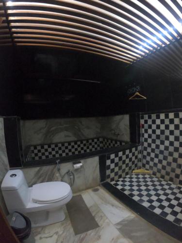 a bathroom with a toilet and a checkered floor at Moustache Jaisalmer in Jaisalmer