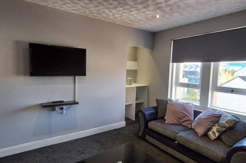a living room with a couch and a flat screen tv at Zara Apartments in Dundee