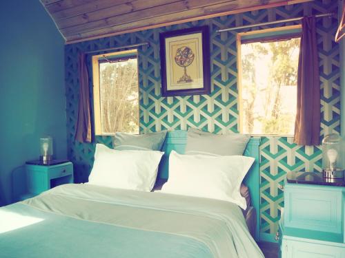 a blue bedroom with a bed and two windows at La Gare De Millas Chambres d'hôtes in Millas