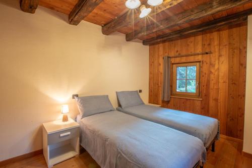 een slaapkamer met twee bedden en een raam bij L'Atelier du Temps - Les Greniers Appartements in Aosta