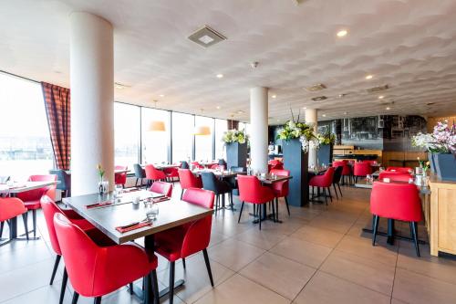 a dining room with red chairs and tables in a restaurant at Bastion Hotel Groningen in Groningen