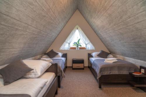 a attic room with two beds and a window at Apartamenty "Góralskie Kąty" agroturystyka in Szaflary