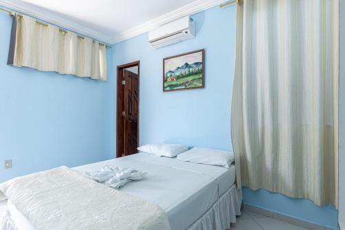 a blue bedroom with two beds and a window at Pousada Santa Fé in Aracaju