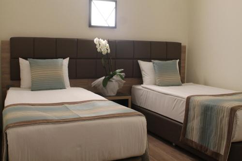 a room with two beds and a vase of flowers at Kimeros Park Holiday Village - Ultra All Inc. Kids Concept in Kemer
