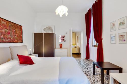 sypialnia z białym łóżkiem i czerwonymi zasłonami w obiekcie Accogliente appartamento a Dorsoduro con GIARDINO! w Wenecji