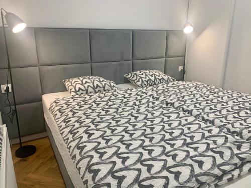 a bed with a black and white comforter and two pillows at Apartamenty Asapartment Stockholm in Olsztyn