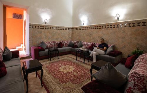 a man sitting on a couch in a living room at Hotel Toulousain in Marrakech