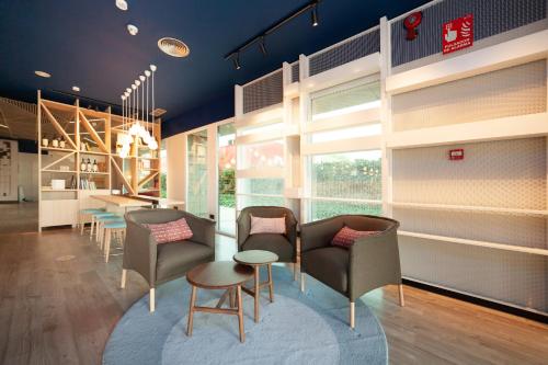 a waiting area with chairs and tables in a building at Ibis Alcala de Henares La Garena in Alcalá de Henares