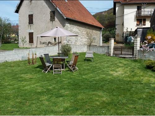 una mesa y sillas con una sombrilla en un patio en Gîte des 3 Hiboux, en Mondon