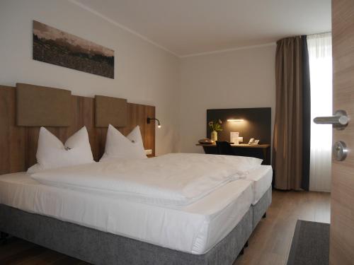 1 dormitorio con 1 cama grande con sábanas blancas en Anderschitz Landhotel, en Neufarn