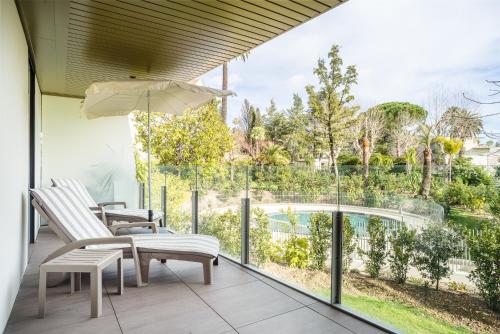- un balcon avec vue sur la piscine, 2 chaises et un parasol dans l'établissement Parc Eugenie by Welcome to Cannes, à Cannes