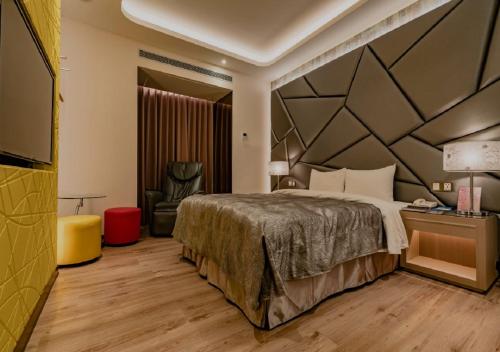 a hotel room with a bed and a chair at Eusta Motel in Taichung