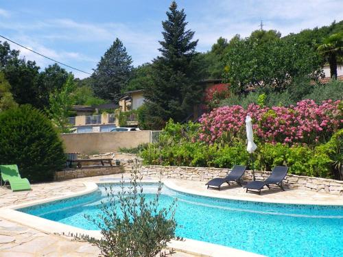 een zwembad met 2 ligstoelen naast een tuin bij Mas Du Cadranier in Villeneuve