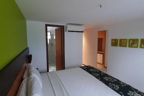 a bedroom with a white bed and a green wall at Natal Plaza requinte, conforto e vista para o mar in Natal