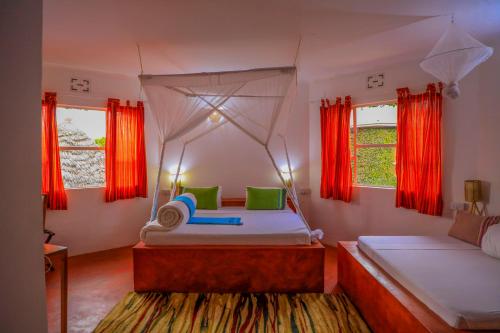 a bedroom with two beds and red curtains at Dan Stam Hotel in Arusha