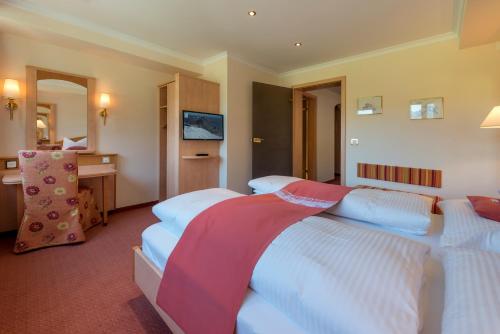 a hotel room with three beds and a desk at Alpenresort Eienwäldli Engelberg in Engelberg