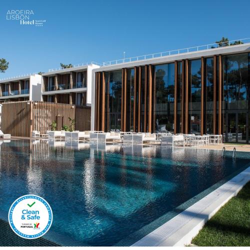 a swimming pool in front of a building with white chairs at Aroeira Lisbon Hotel - Sea & Golf in Aroeira